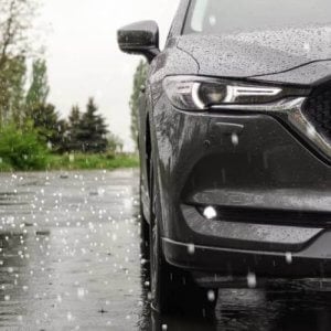 A black car uncovered in a hail storm.