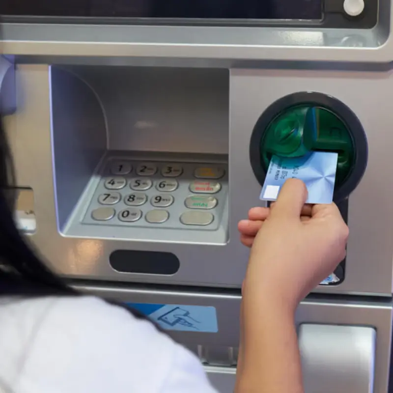 A woman putting her credit card into an ATM