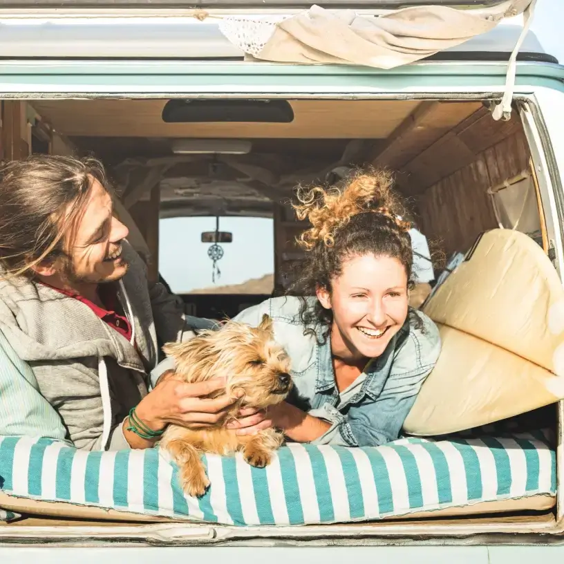 Couple and their dog with surfboard lying in a van
