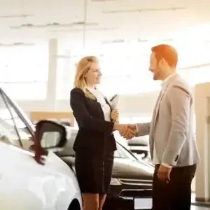A man shaking the hand of a car salesperson at a dealership.