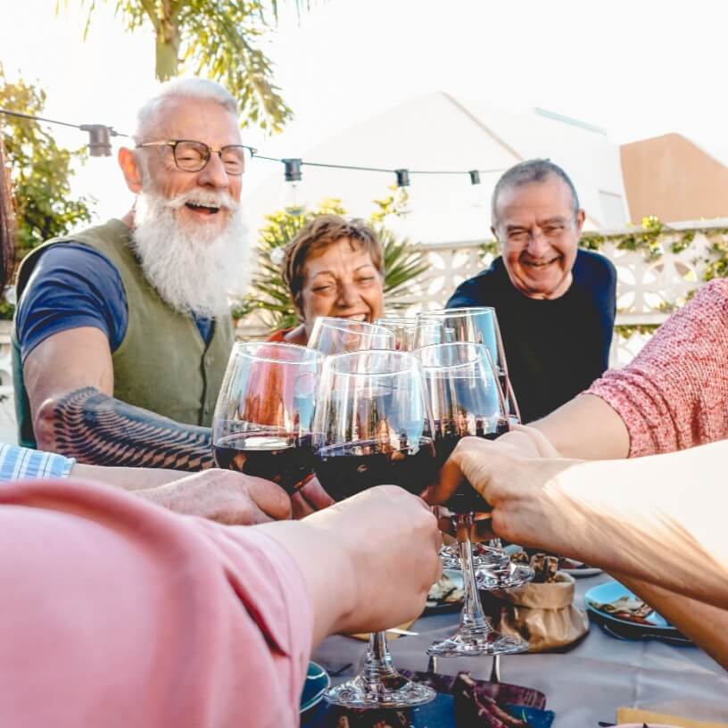 Older couples cheering one another with a glass of wine each
