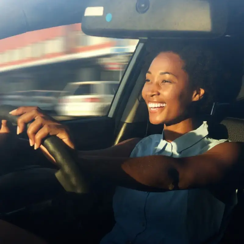 A happy woman driving her car.