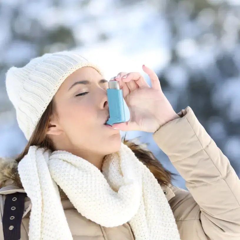 Woman in winter clothes using an asthma puffer