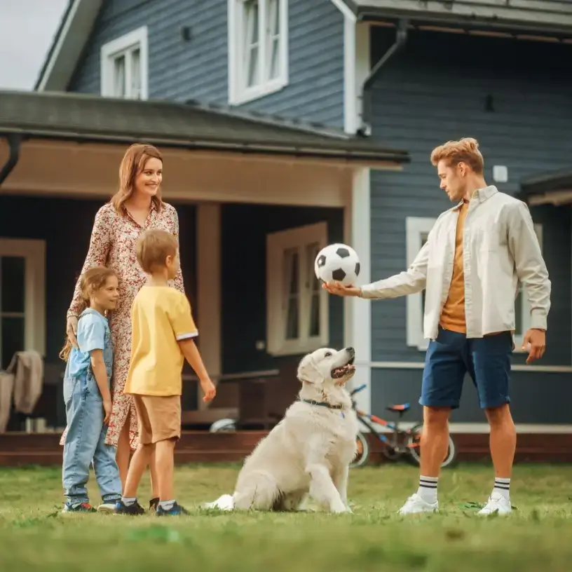 A young family in their yard playing with their dog.