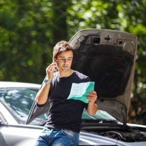 A man on the phone with insurer, holding a copy of his policy.