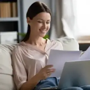 A woman on a couch reading her claim notice.