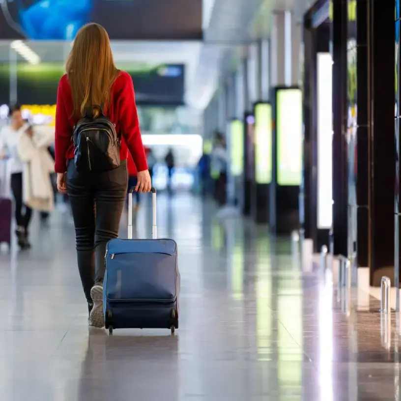 A woman walking while dragging her luggage at an airport.