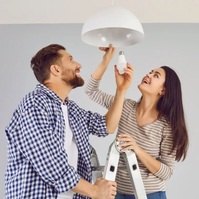 A couple replacing a lightbulb.
