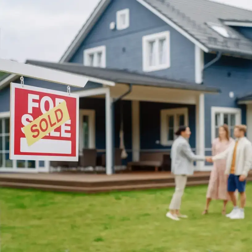 Couple buying house beside 'Sold' sign