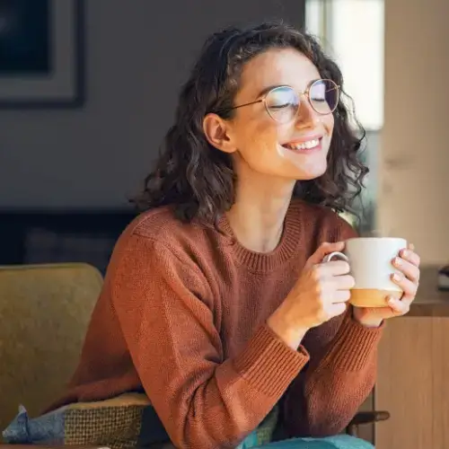Woman on couch with warm drink and blanket