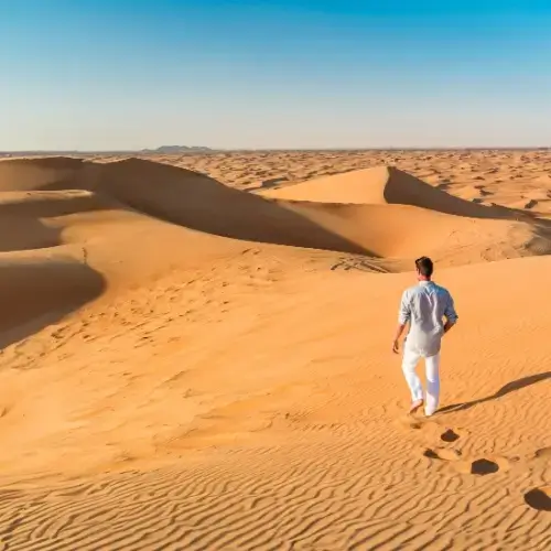 Man walking across sand dunes in Dubai United Arab Emirates
