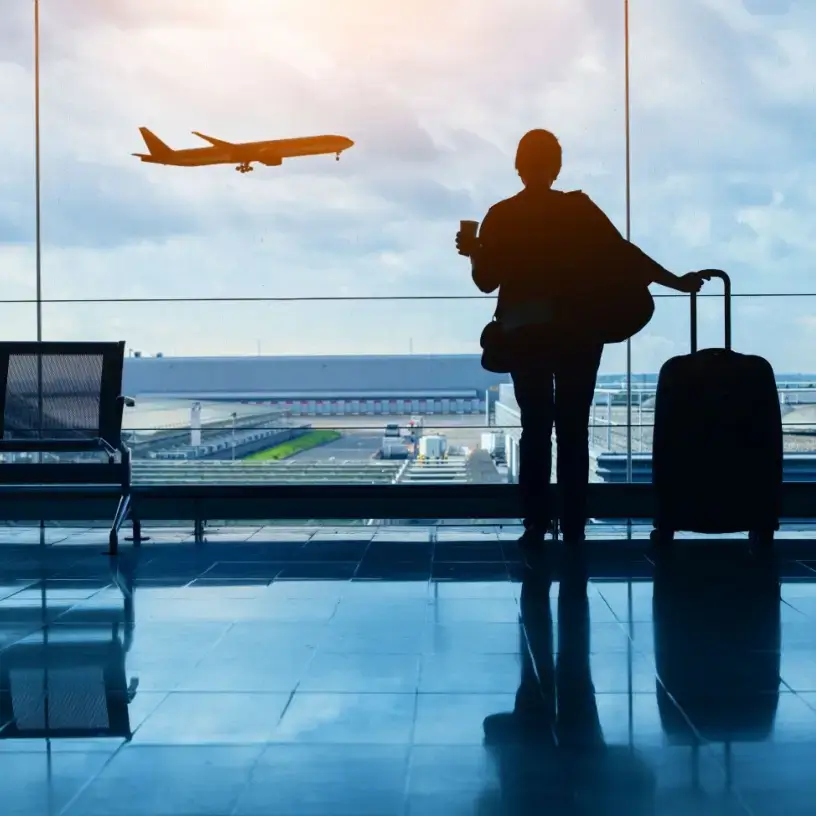Traveller in airport watching plane outside the window