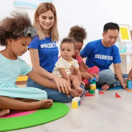 Volunteers playing with children in childcare centre