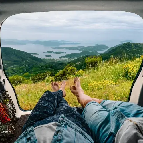 People in car on road trip overlooking mountain landscape