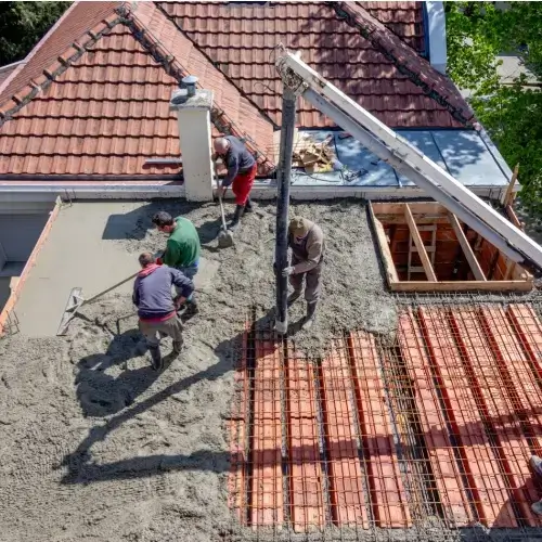 Workers building concrete slab on house