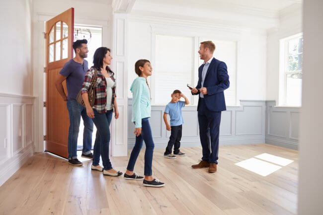 Family entering home for sale with real estate agent