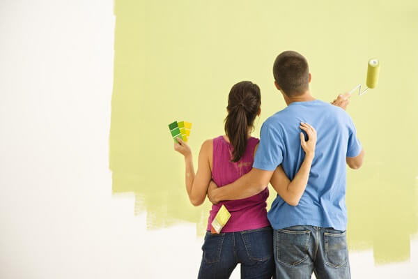 couple painting a wall green 