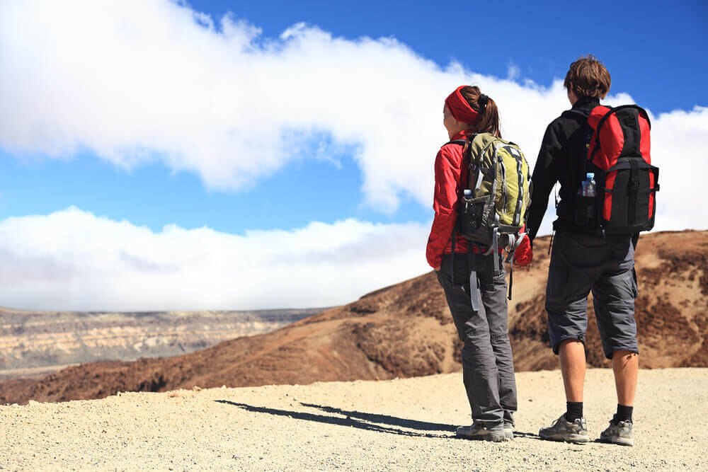 couple holding hands and standing over a deserted cliff