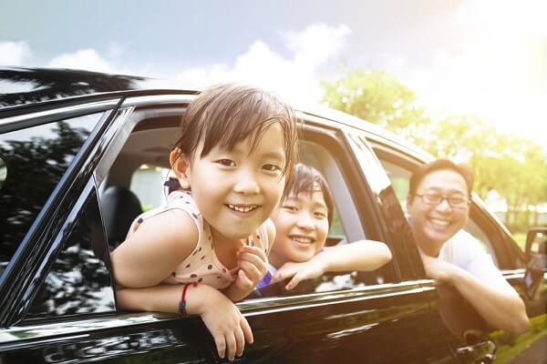 kids and parent looking out the window of a car