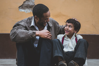 Father and son sit and smile