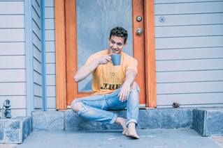 Man having coffee on porch in front of house