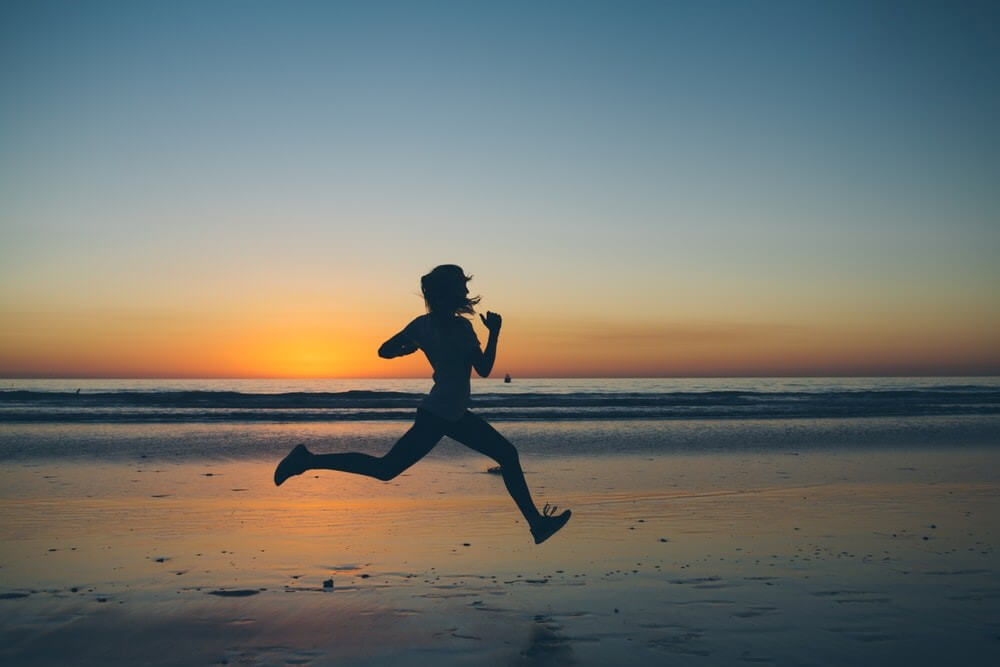 Woman Running On Beach At Sunset
