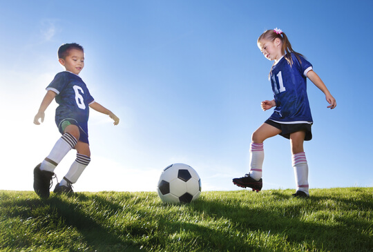 young-boy-and-girl-playing-soccer-on-a-grass-field-in-team-uniform