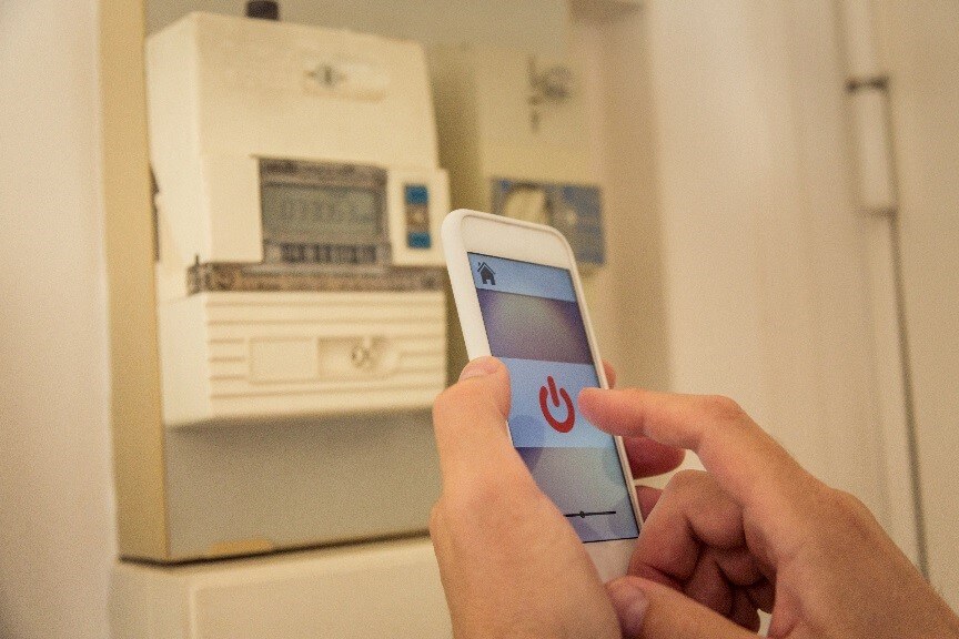 Person checking electricity consumption through smart meter on mobile phone app