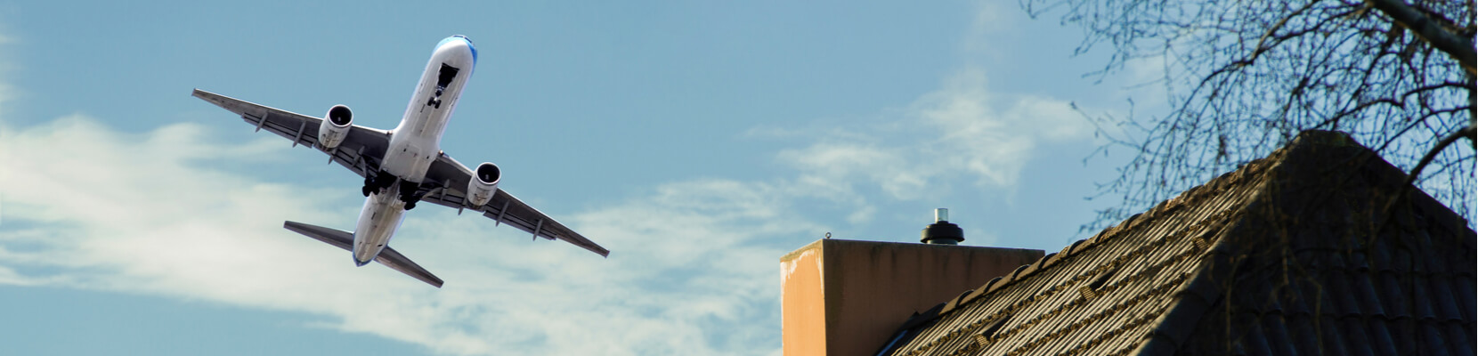 passenger jet flies over a house roof