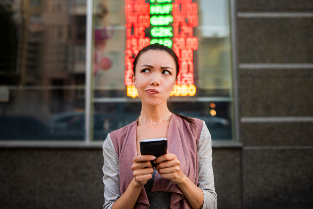 A woman using an application on her smart phone to check currency exchange rates. 