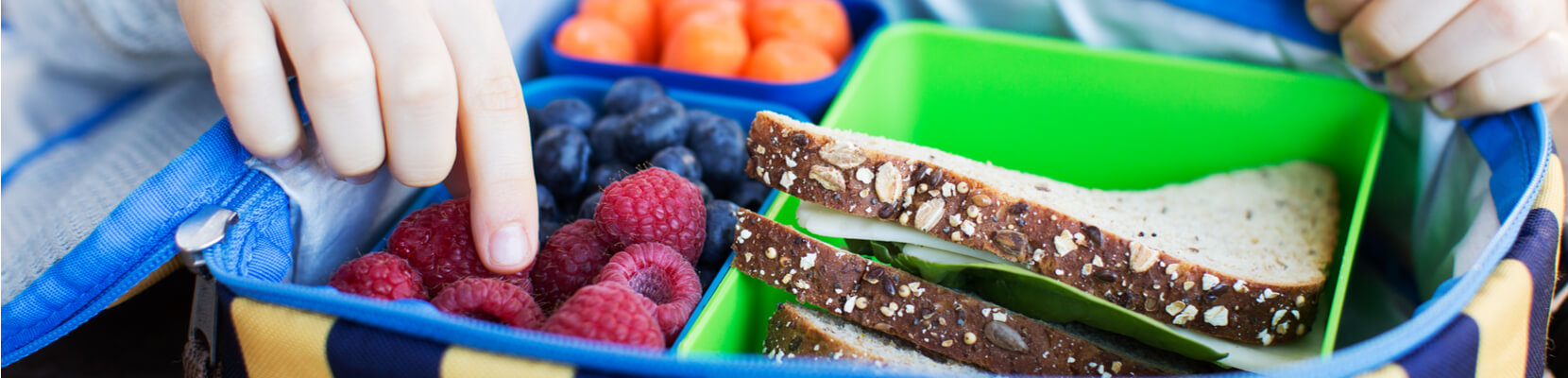 child taking food out of lunchbox