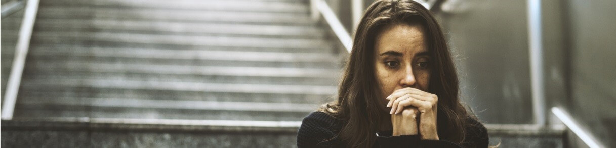 woman sitting on stairs with hands clasped