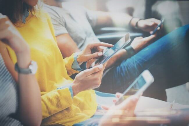 people using their mobile phones while sitting together