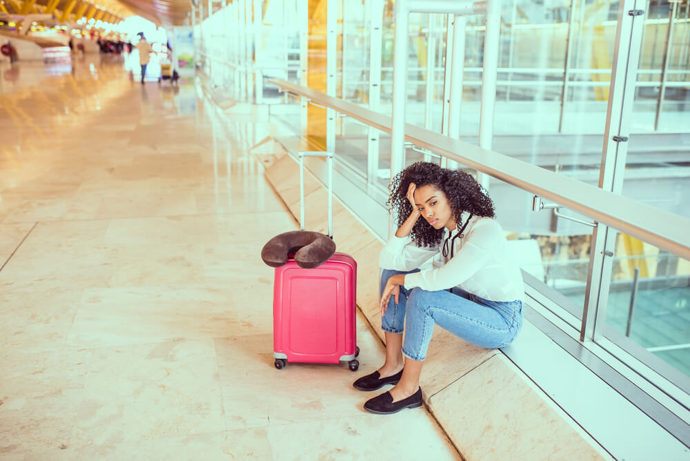woman at airport waiting flight cancelled delayed