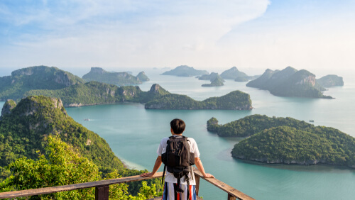 Man tourist with backpack are looking at the beautiful natural landscape of the sea on peak view point of Ko Wua Ta Lap island in Mu Ko Ang Thong National Park, Surat Thani, Thailand