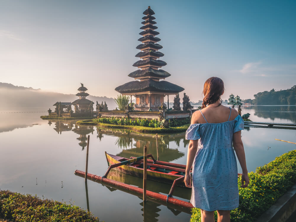 Woman near Pura Ulun Danu Bratan temple in Bali island, Indonesia at sunrise