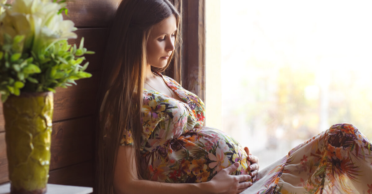 A pregnant woman in a dress lying against the wall