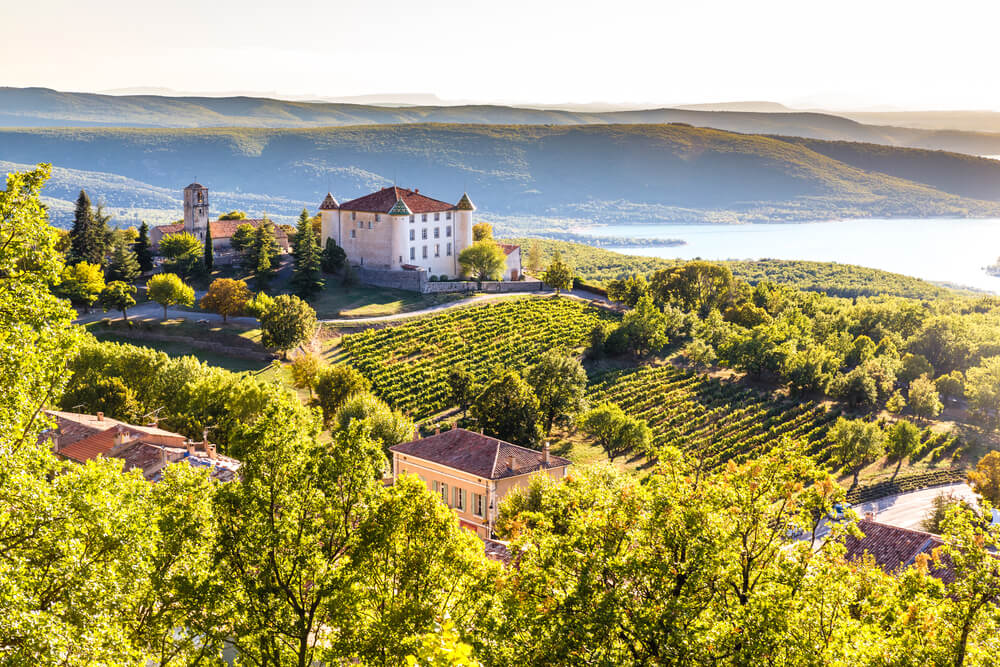 View Of Aiguines Village And Renaissance-style Chateau Overlooking Lac de Sainte Croix Lake-Alpes de Haute Provence, France