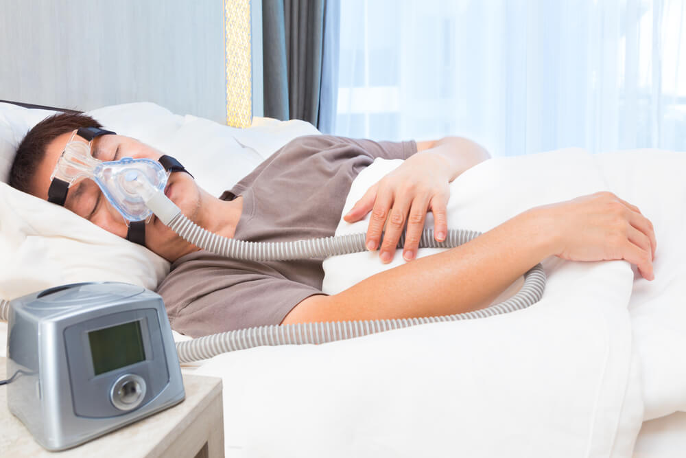 a man using a CPAP machine in bed