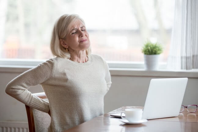 Older woman with hands on her lower back in pain