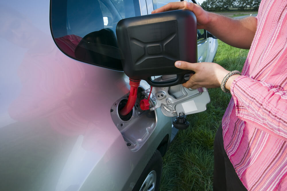 Man refuelling his car with a jerry can of petrol