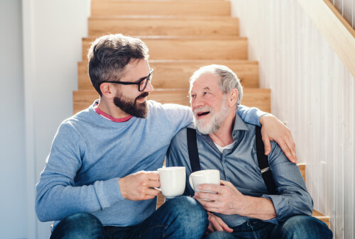 a young man and an old man sitting on stairs drinking tea