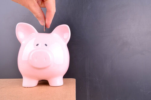 someone putting a coin into a piggy bank