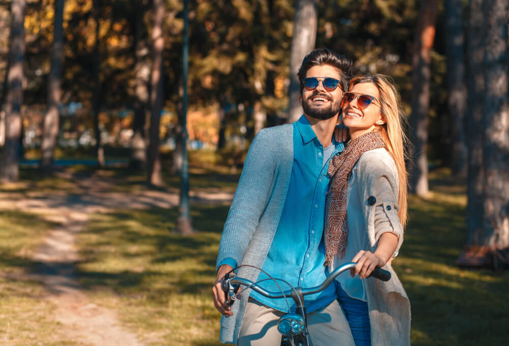 young couple in the forest wearing sunglasses smiling