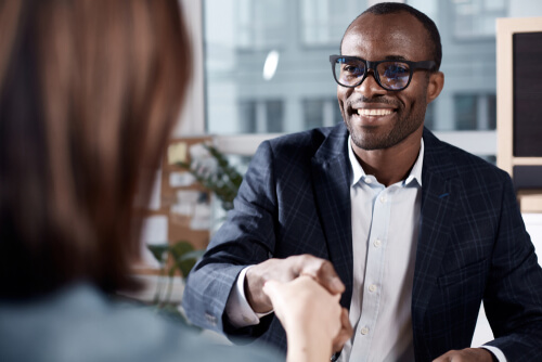 a smiling man in a suit shaking hands with a woman