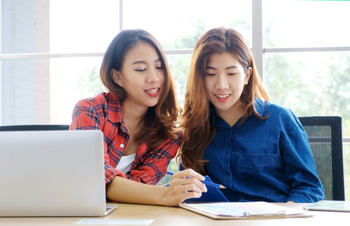 two sisters using a computer and a notebook