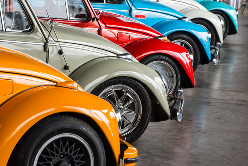 different coloured Volkswagen Beetles parked in a line