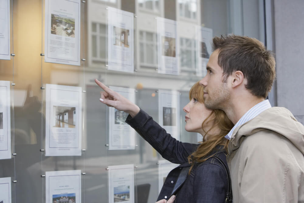 A couple choosing a property from a real estate window display