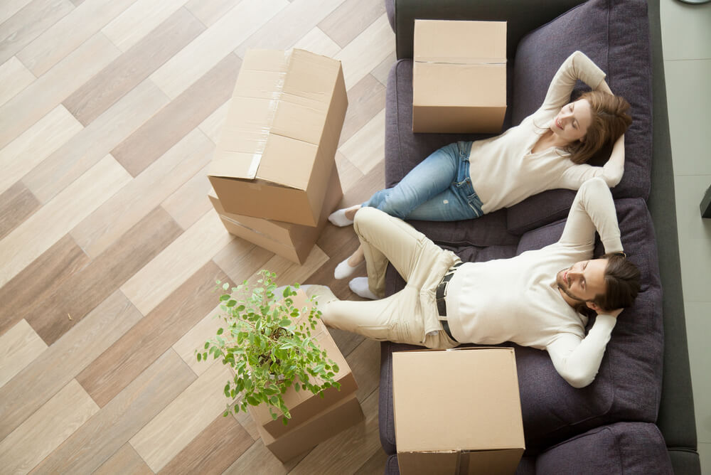 A couple relaxing on couch with boxes after moving into rental property