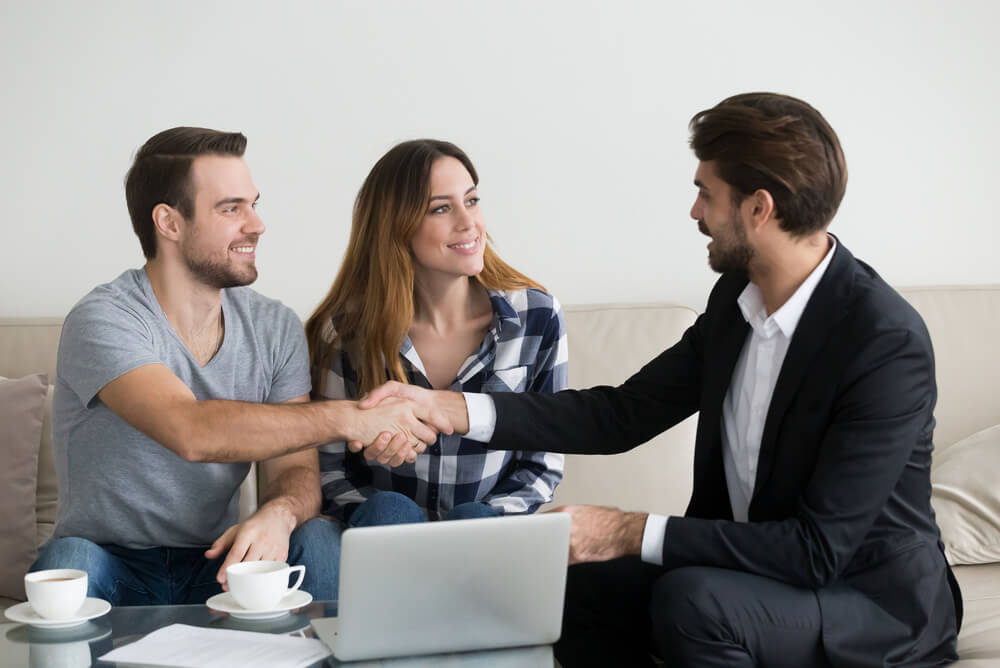 A young couple asking property agent what is rental insurance when signing rental property agreement